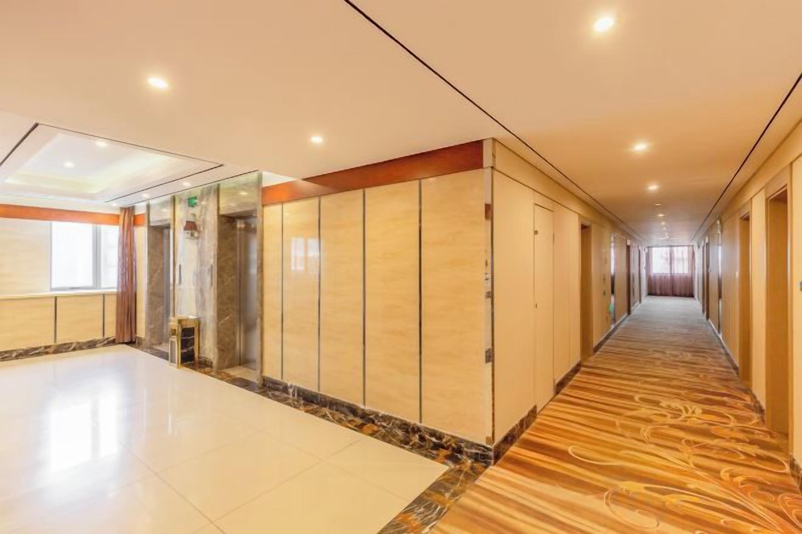 Un pasillo de hotel con piso de mármol, paneles de madera y una larga extensión.