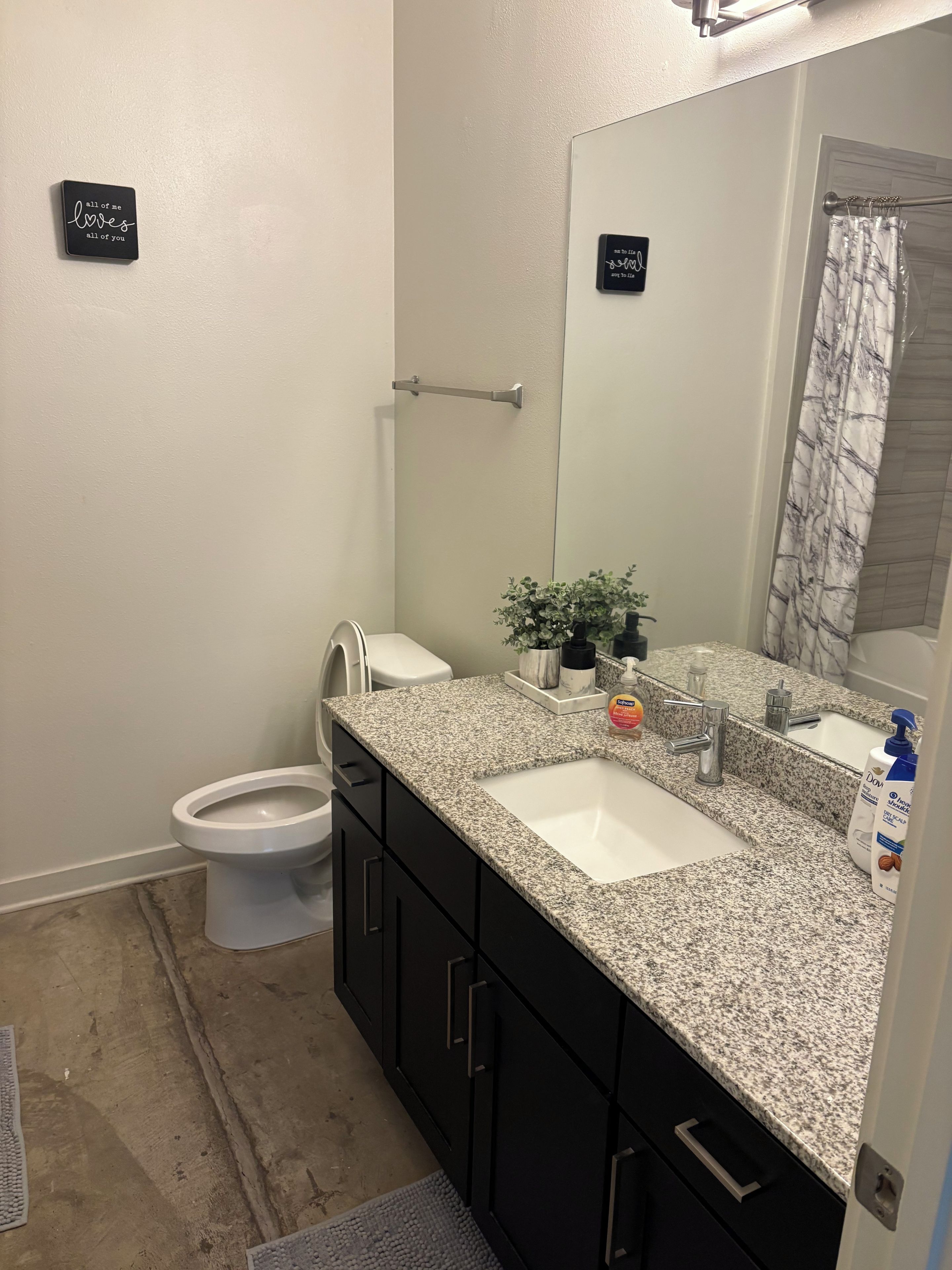 A bathroom with a toilet, sink, mirror, and a towel rack.