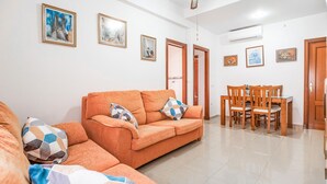 A living room with a sofa, a dining table with chairs, and several framed pictures on the walls. - 2 bedroom nice apartment in Chipiona (Chipiona)