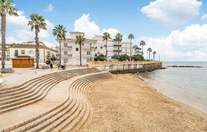 A beach with a curved staircase leading to a promenade, palm trees, and a building with balconies. - 2 bedroom nice apartment in Chipiona (Chipiona)