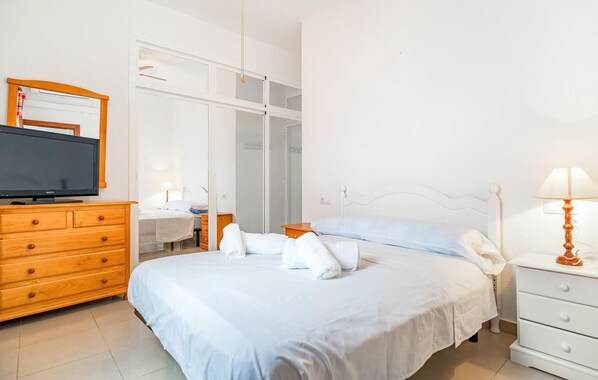 A hotel room with a bed, a wooden dresser, a television, a lamp, and a mirror. - 2 bedroom nice apartment in Chipiona (Chipiona)