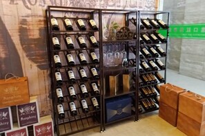 A wine rack with multiple bottles, a small table with a decorative item, and a green sign in the background.