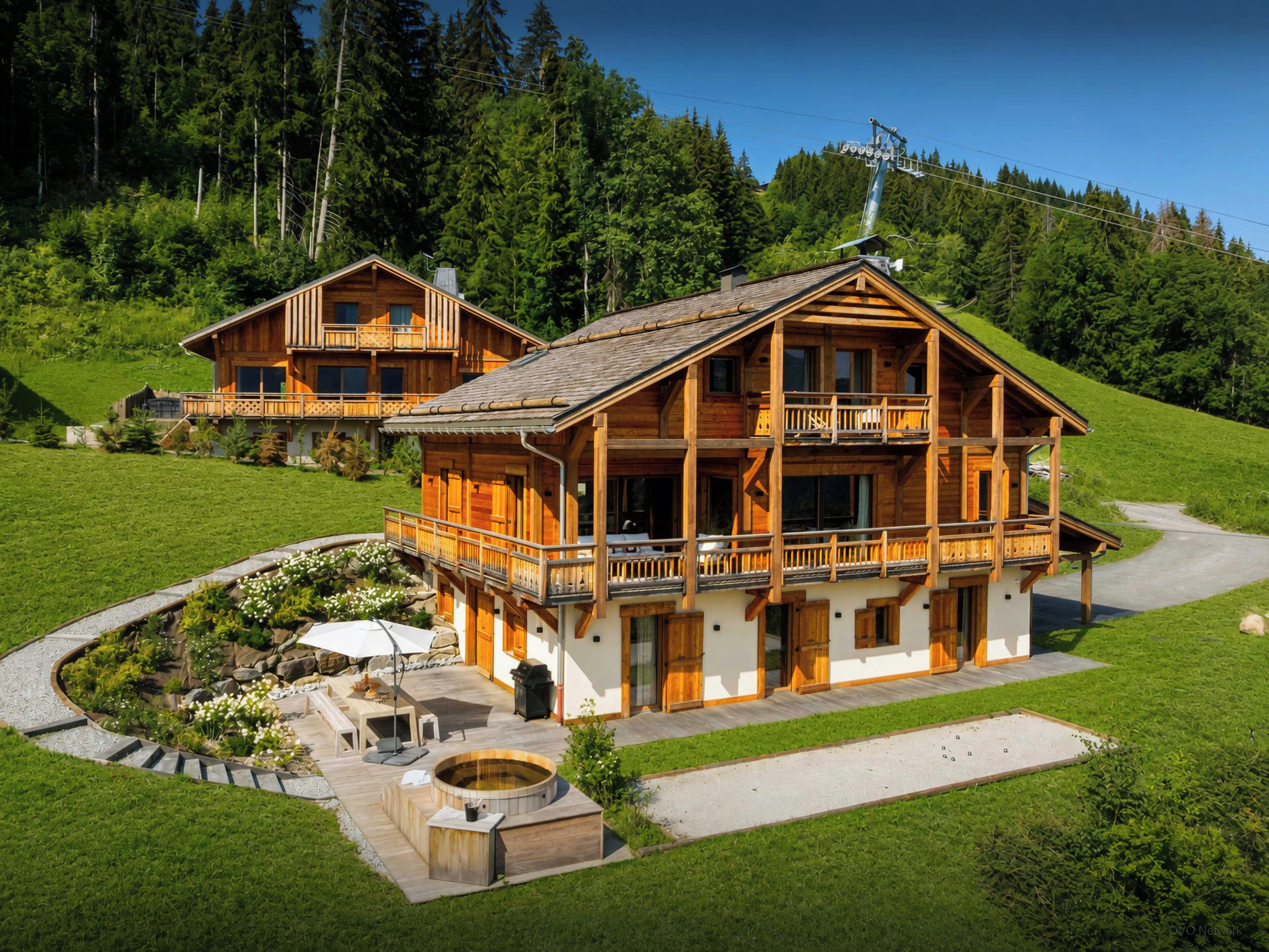 Un chalet de madera de dos pisos con balcón, jacuzzi y jardín ajardinado.