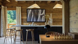 Ein Holzinterieur mit Barbereich, einem Esstisch mit Schachspiel und einem großen Kunstwerk an der Wand.