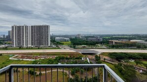 A high-rise building with a modern design, surrounded by a mix of greenery and other urban structures. - Simple And Warm Studio At Casa De Parco Apartment (Pagedangan)