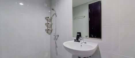 A modern bathroom with white tiles, a white sink, a mirror, and a shower with a handheld showerhead.