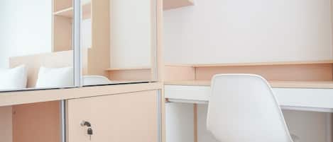 A modern, minimalist office space with a wooden desk, white chair, and built-in shelving.