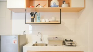 A kitchen with a refrigerator, sink, and a stove. There are cabinets and a shelf above the sink. - Comfort Designed 2Br At Tokyo Riverside Pik 2 Apartment (Teluknaga)