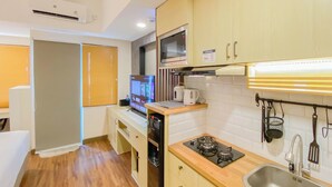 A compact kitchen with a microwave, stove, sink, and a small countertop. - Minimalist and Cozy Studio LRT City Jatibening Apartment (Bekasi)