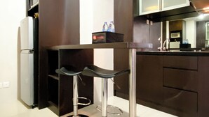 Une cuisine moderne avec des meubles de couleur sombre, un plan de travail blanc et deux tabourets de bar.