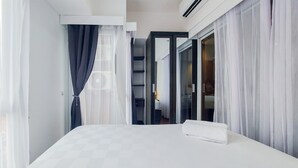 A hotel room with a large bed, a wardrobe, and a bathroom visible through an open door. - Comfy And Minimalist 1Br At Tamansari Bintaro Mansion Apartment (South Tangerang)