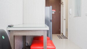A compact kitchen with a refrigerator, a small table, and a red bench. - Best Choice 2Br Parkland Avenue Apartment (South Tangerang)