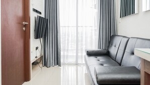 A modern living room with a leather sofa, a glass coffee table, and a TV mounted on the wall. - Best Choice 2Br Parkland Avenue Apartment (South Tangerang)