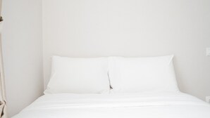 A neatly made bed with white linens in a room with plain white walls. - Best Choice 2Br Parkland Avenue Apartment (South Tangerang)