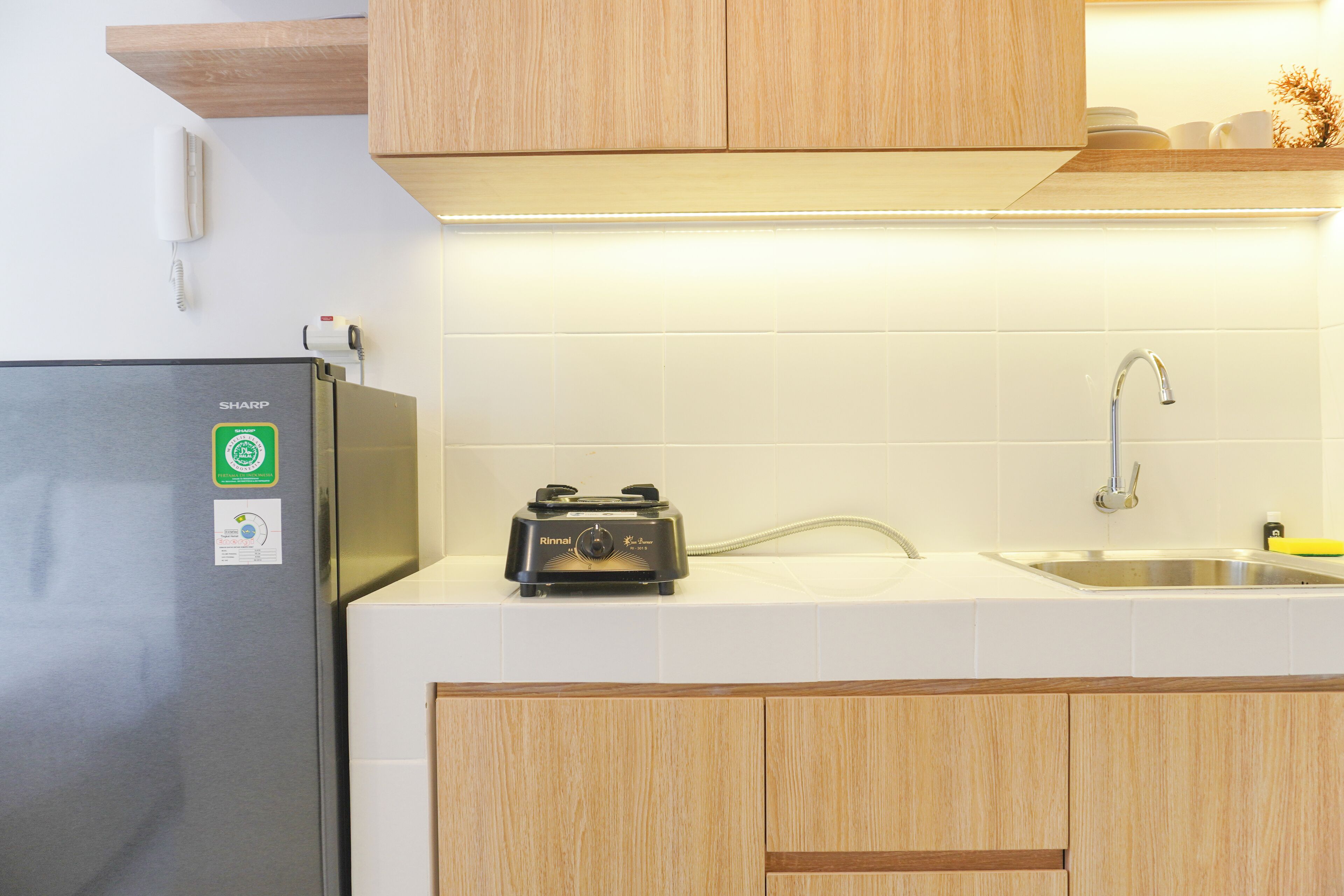 A kitchen with a refrigerator, a toaster, a sink, and wooden cabinets.
