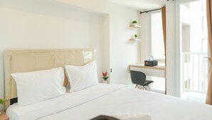 Ein Hotelzimmer mit Bett, Schreibtisch, Stuhl und einem fenster mit Vorhängen.