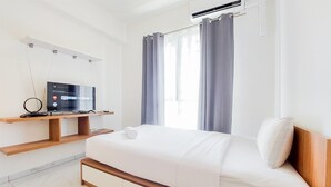 Una habitación de hotel moderna con una cama, un televisor en un estante de madera y una ventana con cortinas.