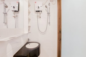 Une salle de bain avec un lavabo blanc, un meuble-lavabo noir et une douche dotée d’un panneau de commande.