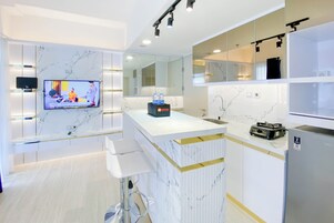 Una cocina moderna con encimeras de mármol, televisor integrado y refrigerador.
