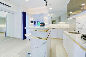 Una cocina moderna con encimera de mármol, un lavamanos empotrado y un televisor montado en la pared.