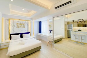 Una habitación de hotel moderna con una cama grande, un escritorio y una kitchenette.