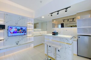 A modern kitchen with a marble backsplash, a built-in TV, and a bar area with stools.