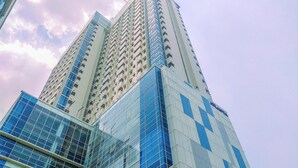 A high-rise building with multiple floors, featuring a mix of glass and concrete facades. - Well Furnished And Cozy 1Br Apartment Atlanta Residences (Depok)