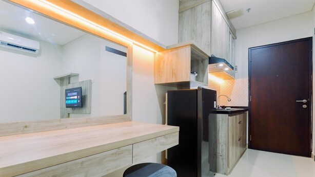 A modern kitchen with a wooden countertop, black appliances, and a wooden cabinet. - Well Furnished And Cozy 1Br Apartment Atlanta Residences (Depok)