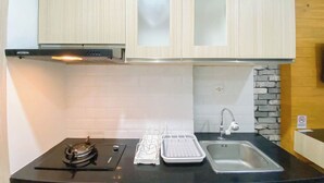 A compact kitchen with a gas stove, a sink, and a cabinet with frosted glass doors.