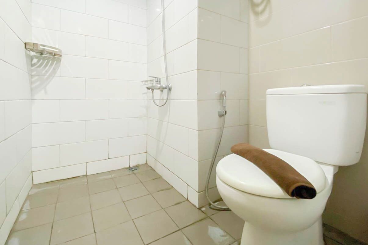 A bathroom with white tiled walls, a white toilet, and a shower area.