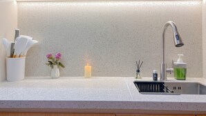 A kitchen with a modern faucet, a candle, and a vase with flowers on the countertop. - Good Studio Apartment LRT City Jatibening (Bekasi)