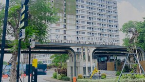 A multi-story hotel with a modern facade, balconies, and a prominent entrance. - Good Studio Apartment LRT City Jatibening (Bekasi)
