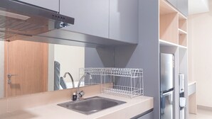 A modern kitchen with a stainless steel sink, a dish rack, and a built-in oven. - Good And Comfort Stay Studio Apartment At B Residence (Pagedangan)