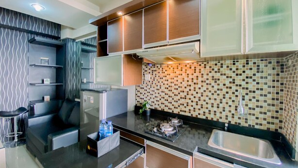 A modern kitchen with a refrigerator, stove, and sink. There are cabinets and a countertop.