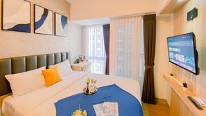Habitación de hotel con cama, escritorio, televisión y obras de arte en la pared.