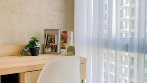 Una habitación moderna con un escritorio de madera, una silla blanca, una planta en maceta, un libro titulado 'Scandinavian Dreaming' y una ventana con cortinas de gasa.
