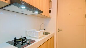 Una cocina compacta con estufa a gas, un lavamanos y armarios de madera.
