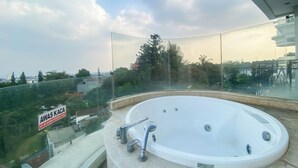 A hot tub on a balcony with a view of a cityscape and greenery. - The Signature Studio Apartment With Jaccuzi Art Deco (Bandung)