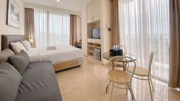 A hotel room with a bed, a sofa, a desk with a computer, and a dining area with chairs. - The Signature Studio Apartment With Jaccuzi Art Deco (Bandung)