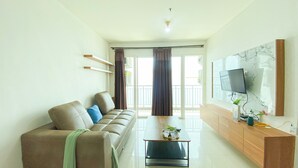 A modern living room with a sofa, a coffee table, and a TV mounted on the wall. - Best Homey And Spacious 3Br At Green Bay Condominium Apartment (Jakarta)