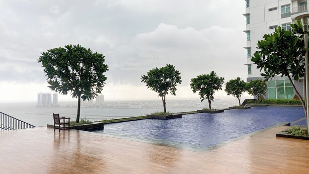 A rooftop pool area with a view of a city skyline and a body of water. - Best Homey And Spacious 3Br At Green Bay Condominium Apartment (Jakarta)
