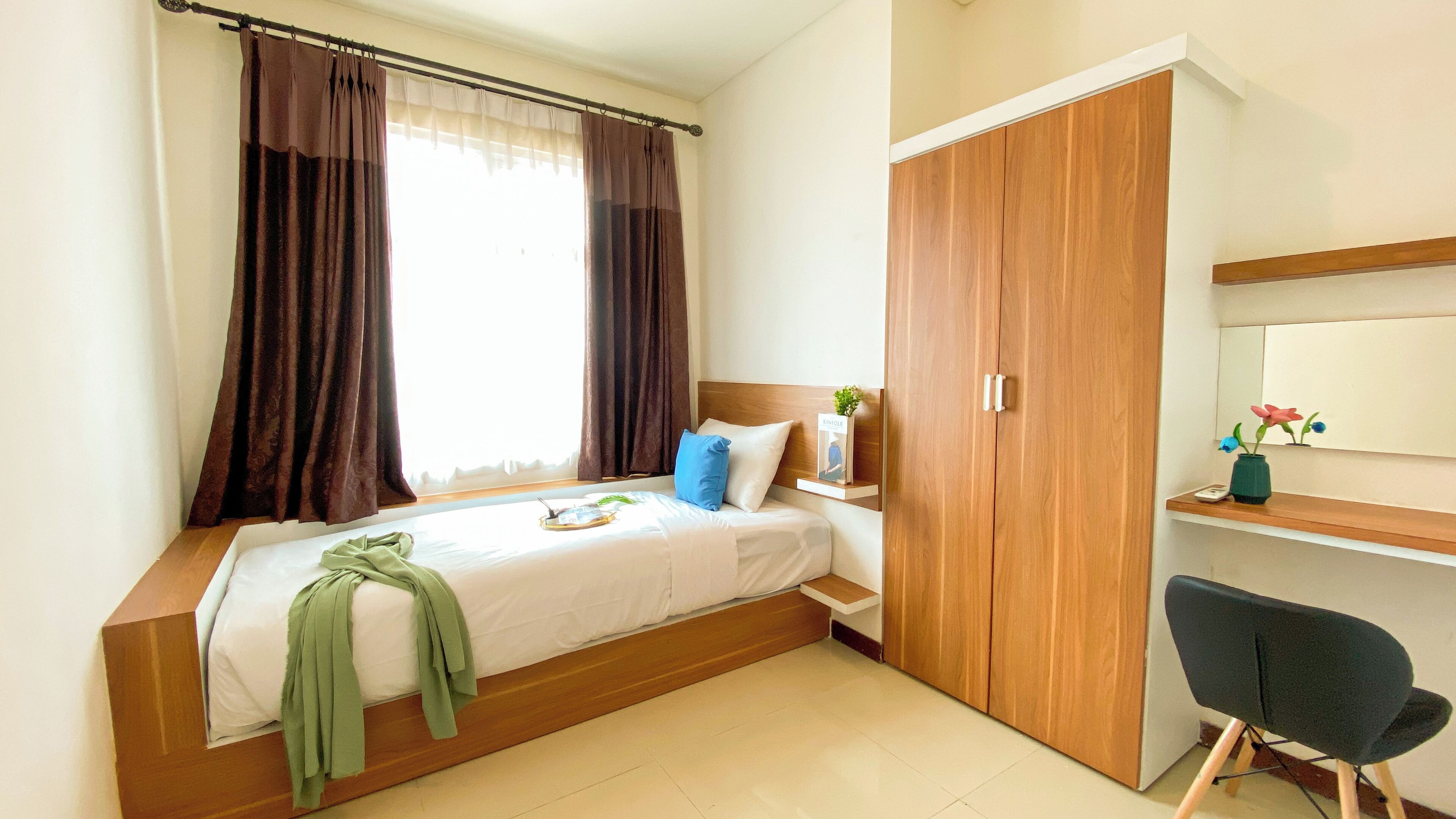 A bedroom with a bed, a nightstand, a wardrobe, a desk, and a chair.
