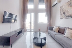 Una sala de estar moderna con un televisor de pantalla plana, una mesa redonda, un sofá y un elemento decorativo en la pared.