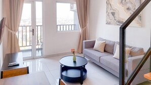 Una sala de estar moderna con un sofá, una mesa redonda de centro con un florero y un cuadro en la pared.