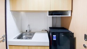 A compact kitchen with a sink, a black refrigerator, and wooden cabinets. - Best Deal And Homey 1Br Without Living Room At The Alton Apartment (Semarang)