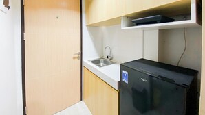 A compact kitchen with a refrigerator, a sink, and wooden cabinets. - Best Deal And Homey 1Br Without Living Room At The Alton Apartment (Semarang)