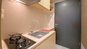 Een kleine keuken met een gasfornuis, een spoelbak en een deur.