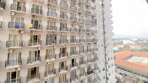 Een hoog appartementencomplex met meerdere balkons, airconditioning en uitzicht op de skyline.