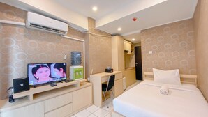 Een hotelkamer met een bed, een bureau, een televisie en een airconditioning.