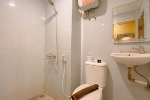 A bathroom with a shower, toilet, sink, and a mirror. - Stylish Studio Apartment At Grand Asia Afrika (Bandung)